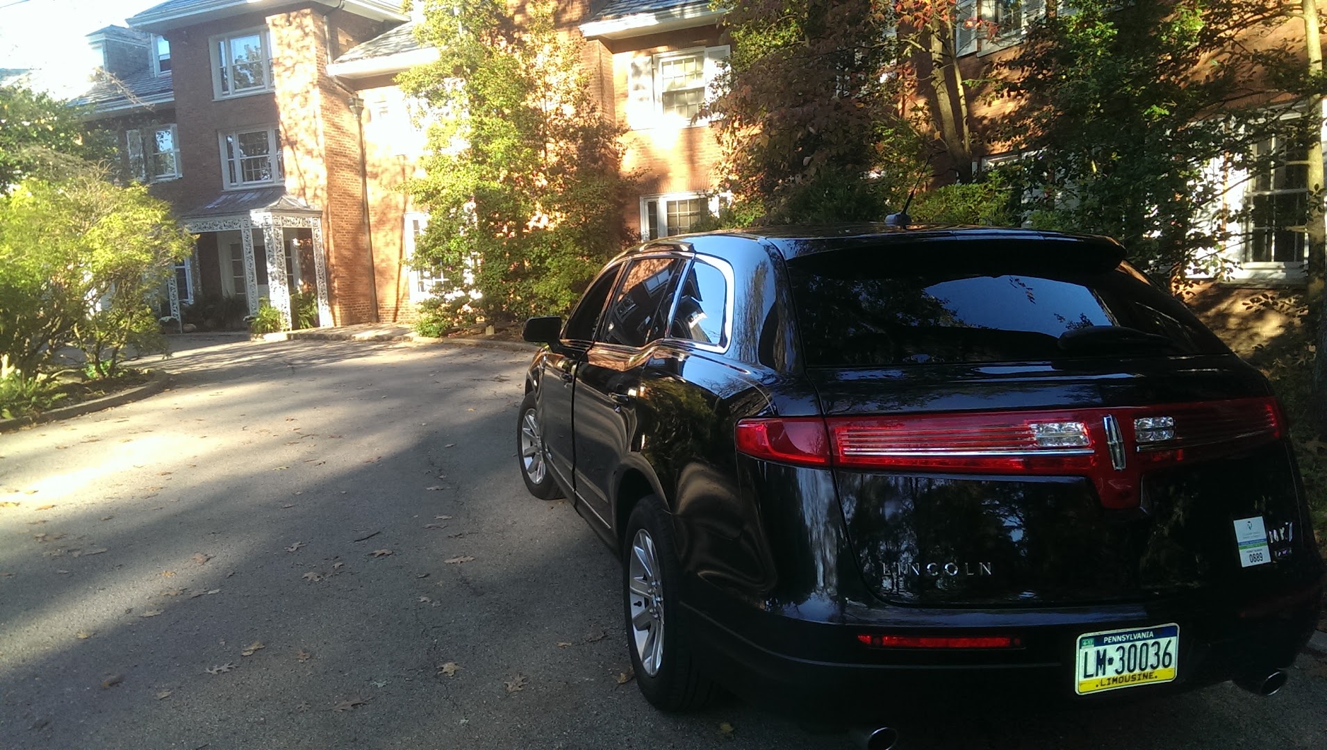 Black Lincoln MKT sedan parked at the entrance of an upscale brick estate